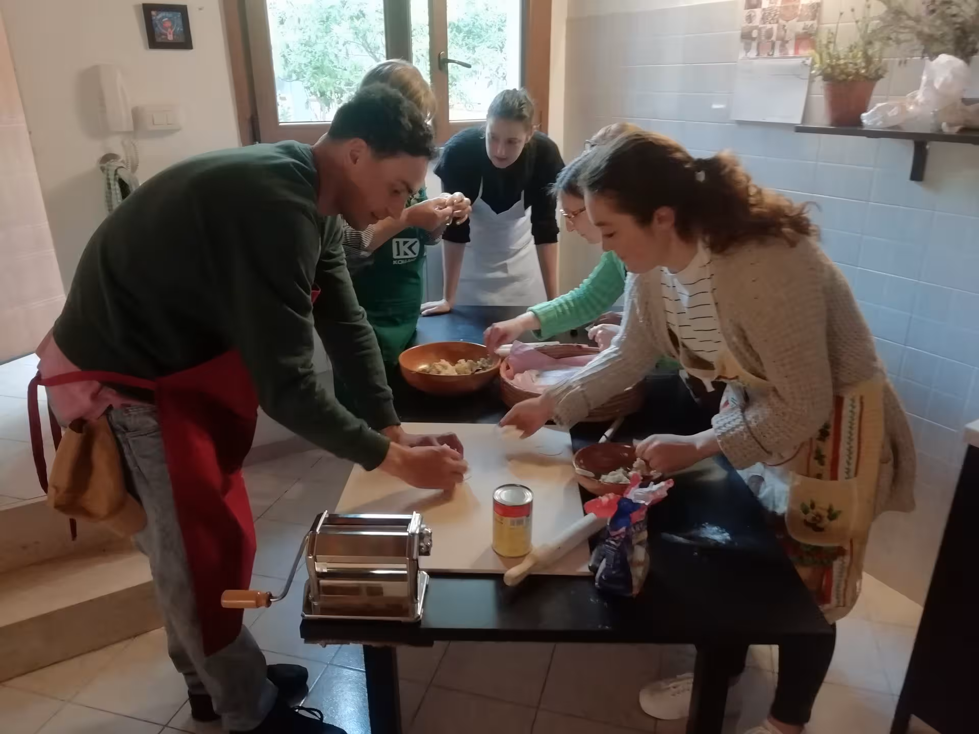 Group of participants in a Cagliari cooking class preparing culurgiones, surrounded by ingredients and pasta tools.