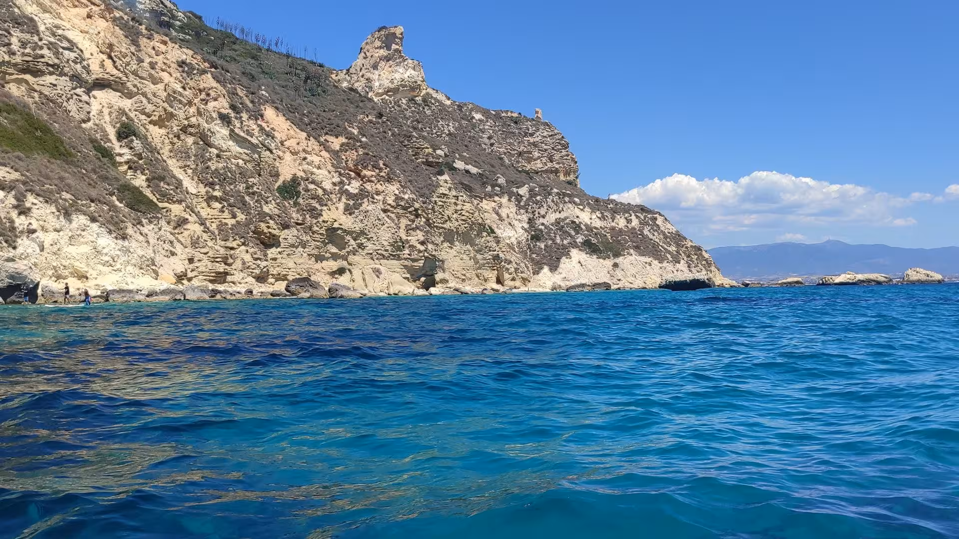 Scenic view of Cagliari's rugged coastline with clear blue waters from a dinghy tour.