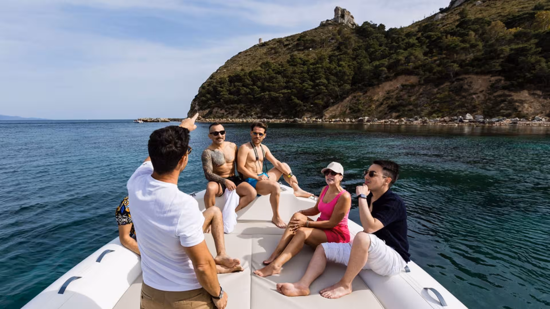Group of tourists enjoying a guided dinghy tour near lush cliffs in the Gulf of Angels, Cagliari.