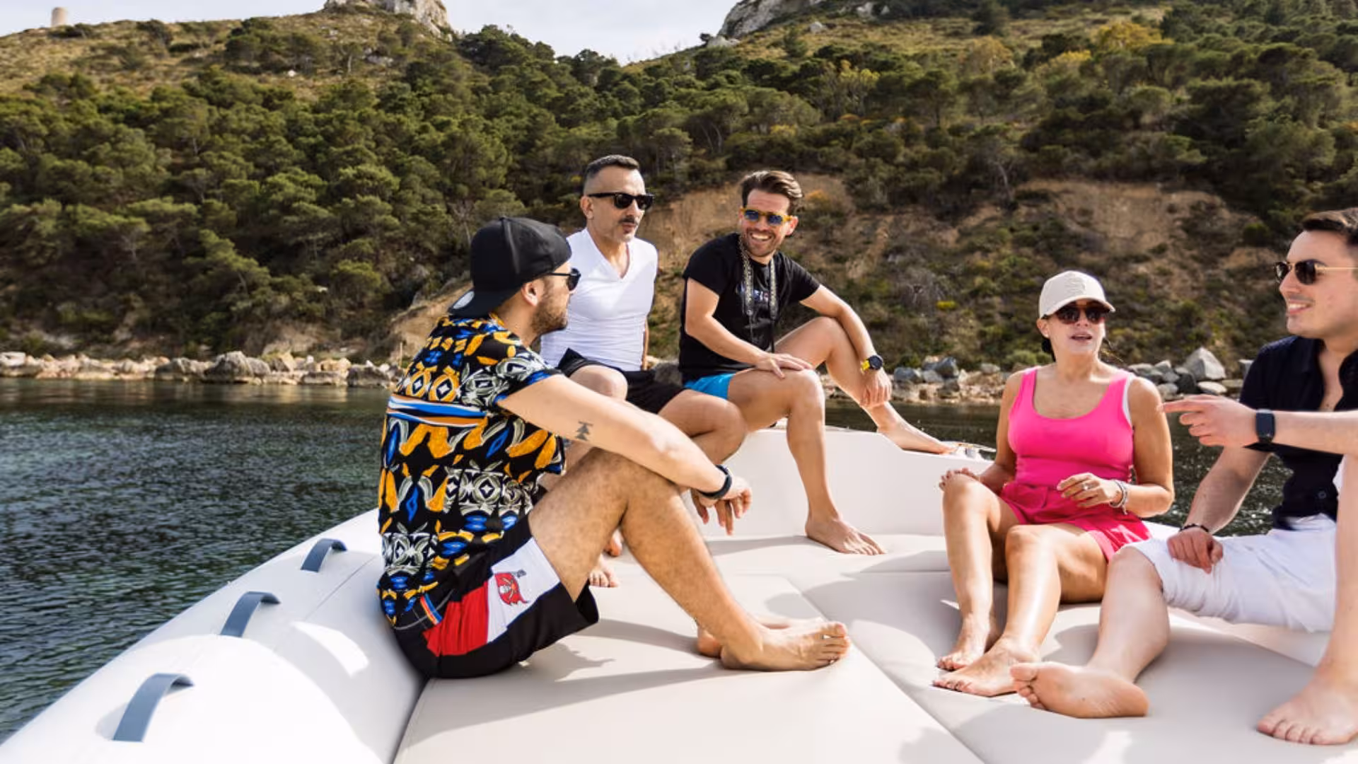 Smiling tourists relax on a dinghy during a scenic tour of the Gulf of Angels, surrounded by rocky landscapes.