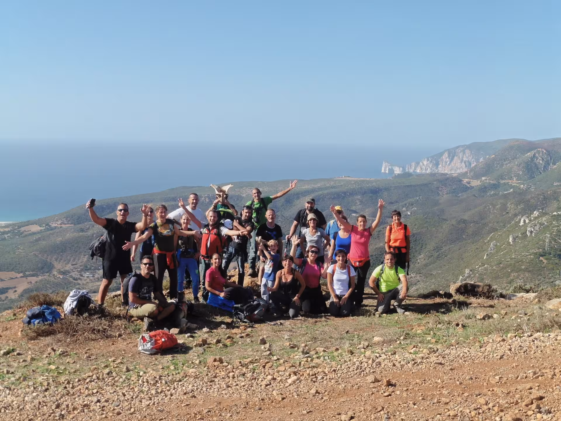 Group of happy hikers on a Cagliari-guided tour with stunning views of Piscinas dunes and coastline.