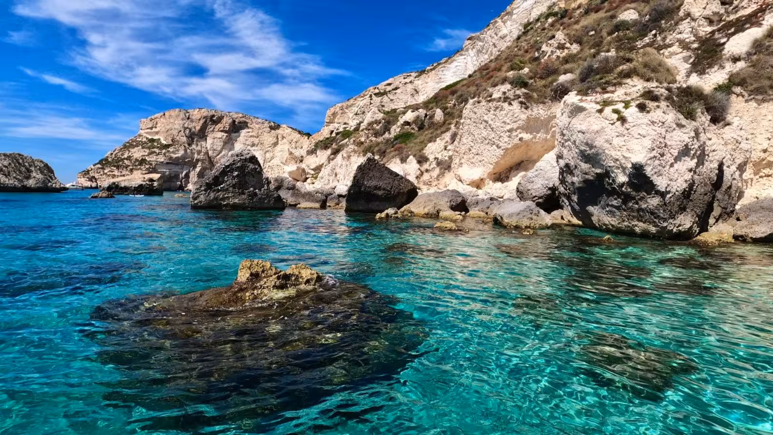 Rocky cliffs and turquoise waters along the scenic coastline of the Gulf of Angels in Cagliari, Sardinia.