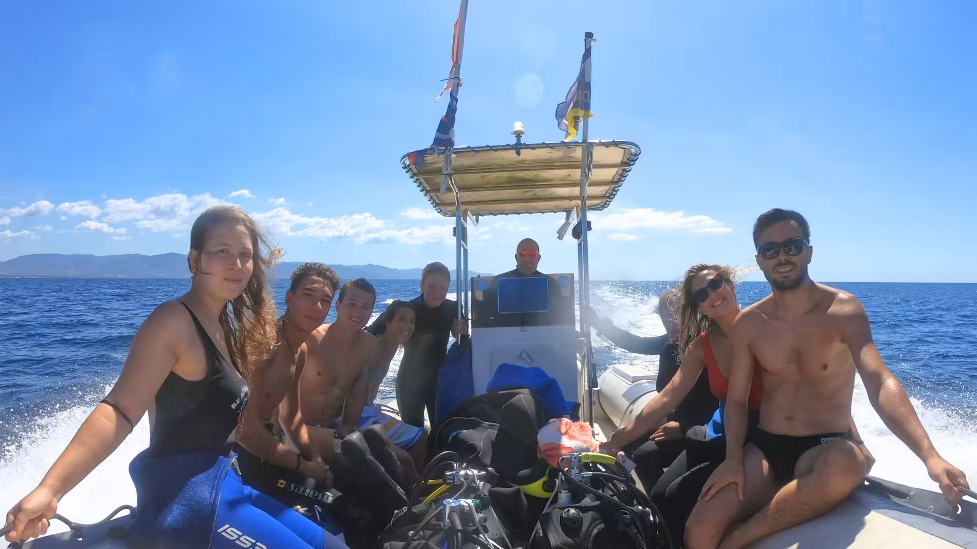 Group of divers enjoys a sunny boat ride in the Gulf of Angels, Cagliari, ready for an underwater adventure.