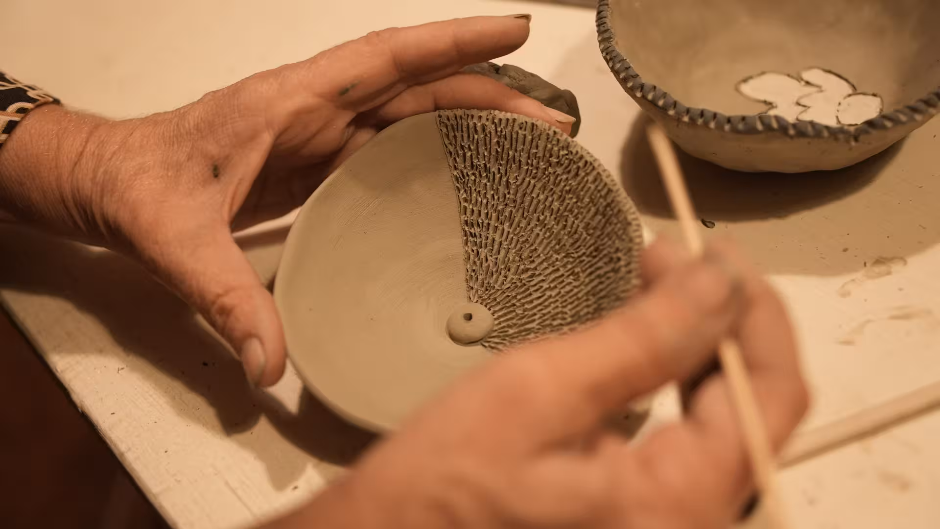 Close-up view of textured clay bowl being handcrafted at a Cagliari ceramics workshop, highlighting intricate design details.