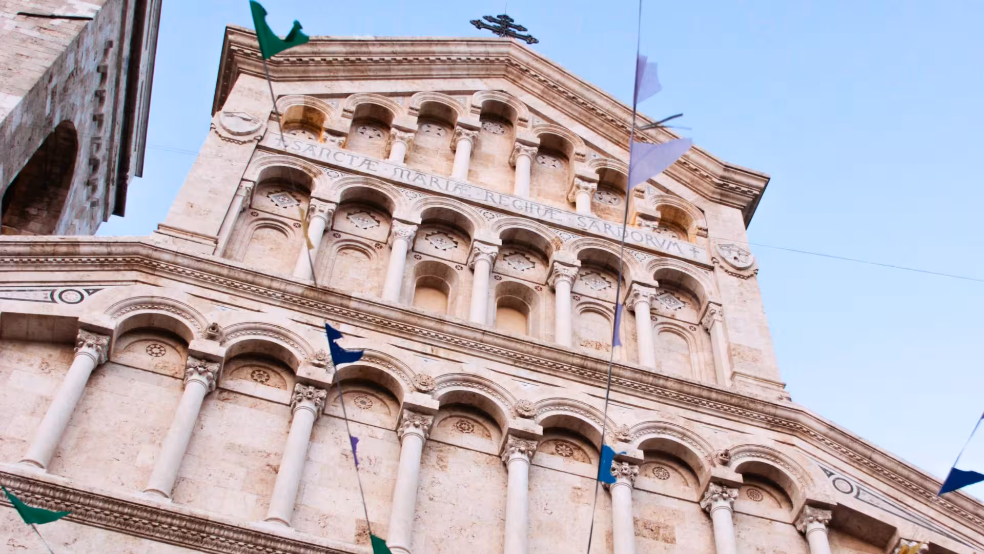 Historic facade in Cagliari's center with colorful flags, ideal for exploring during a food and wine tour.