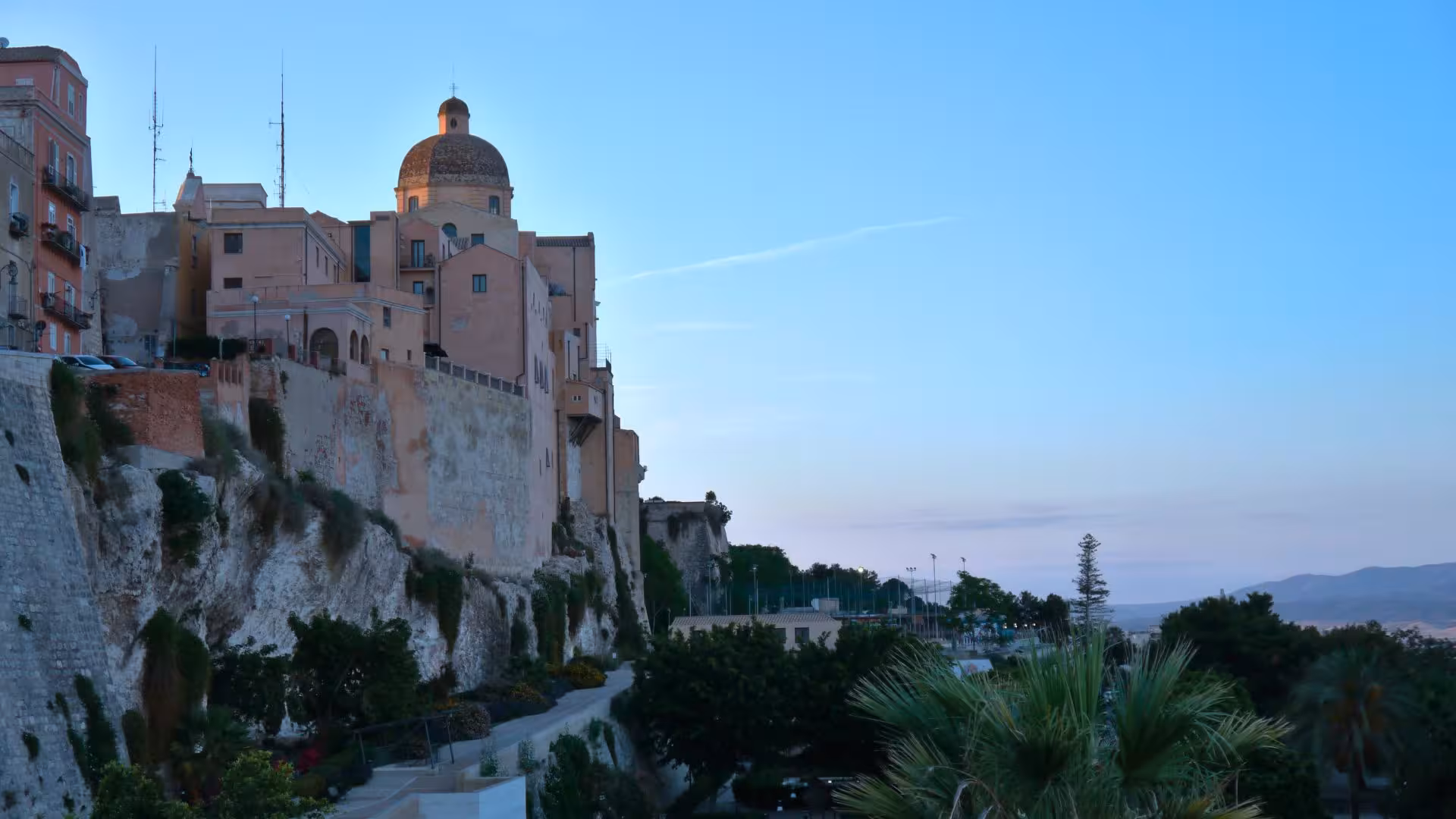 Scenic view of Cagliari's historic center at sunset, featuring charming buildings and coastal beauty on a wine tour.