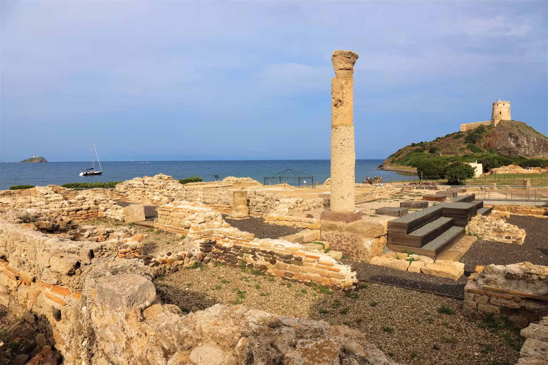 Discover the archaeological site of Nora featuring ancient ruins with a coastal view and historic tower near Cagliari.