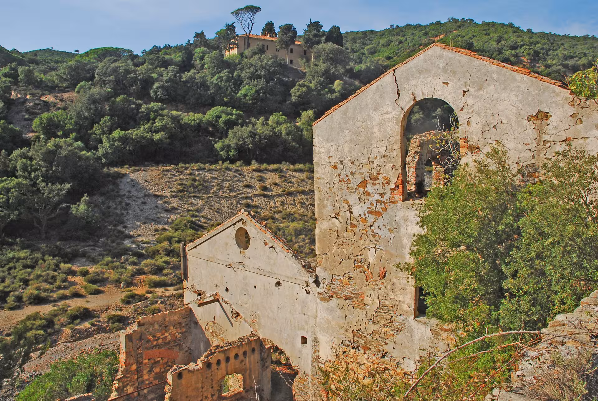 Ruins of ancient buildings surrounded by lush greenery on the Cagliari to Piscinas guided tour.