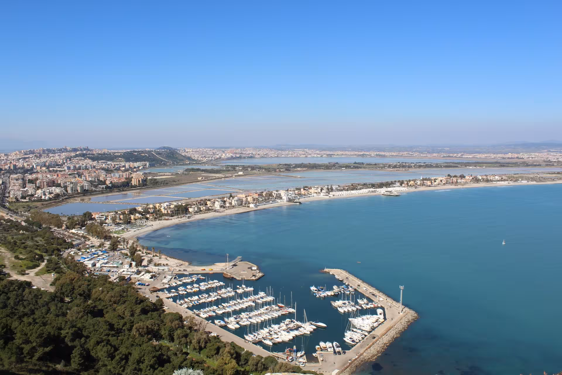 Aerial view of Cagliari's marina and coastline, showcasing the vibrant cityscape and inviting turquoise waters.