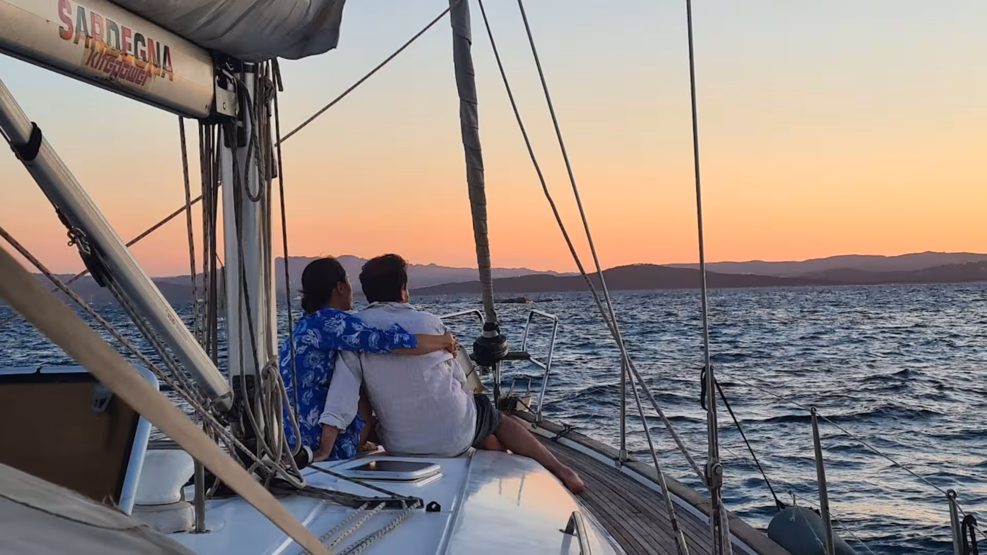 Couple enjoying a romantic sunset view from a sailing boat on a Cagliari 5-hour tour in Sardinia.