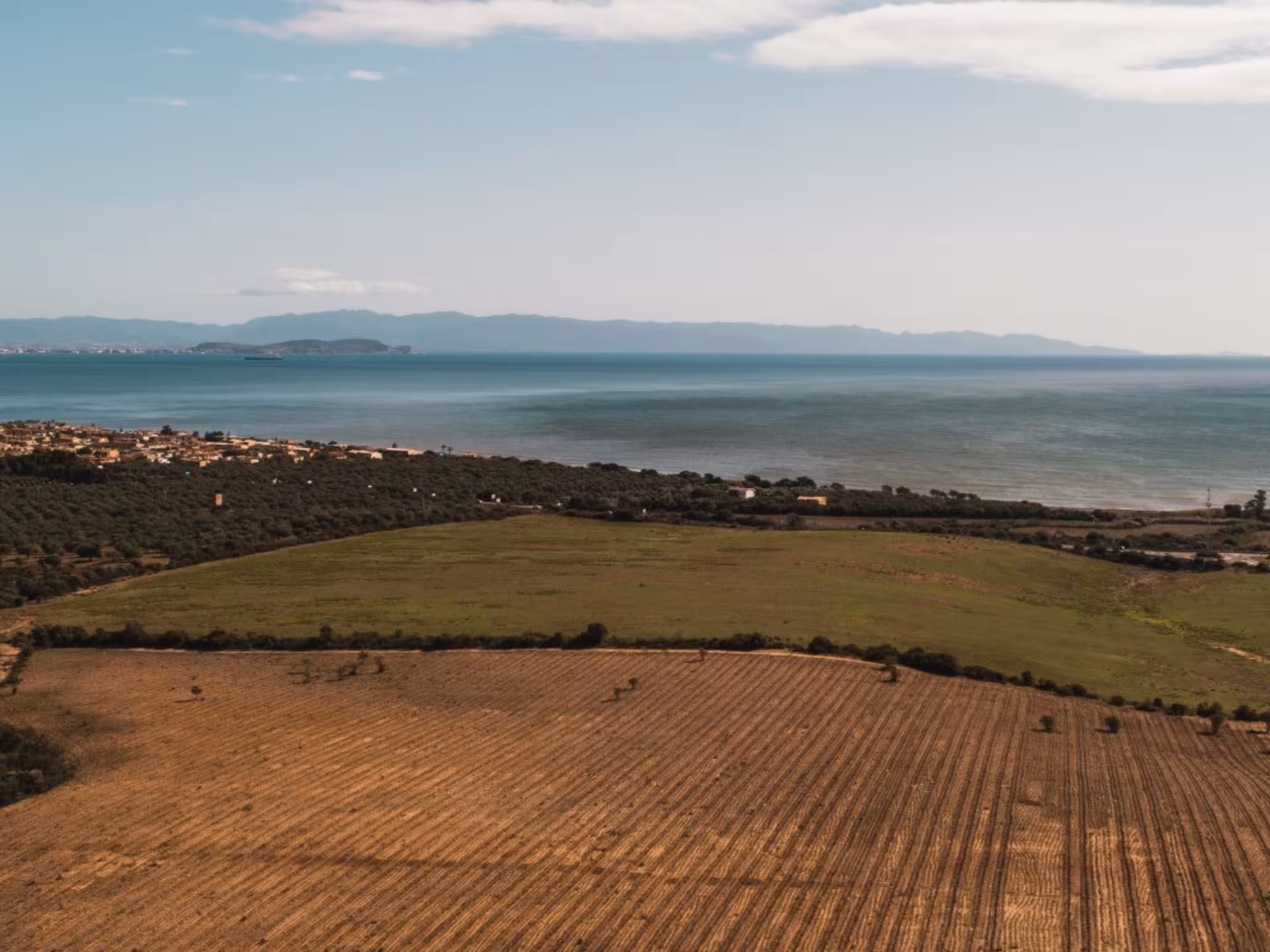 Scenic view of Cagliari countryside hills with vineyards overlooking the serene coastline and azure sea.