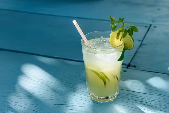 Refreshing Caipirinha cocktail with lime and mint on a sunlit table, perfect for a beach sunset in Brazil.