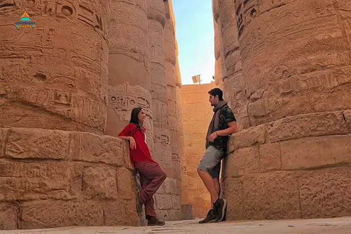 Couple between Karnak Temple columns in Luxor, part of 8 days 7 nights Cairo to Abu Simbel by road