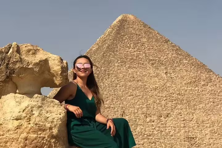 Traveler posing by rocks with the Great Pyramid of Giza on a Cairo Airport layover tour to the pyramids
