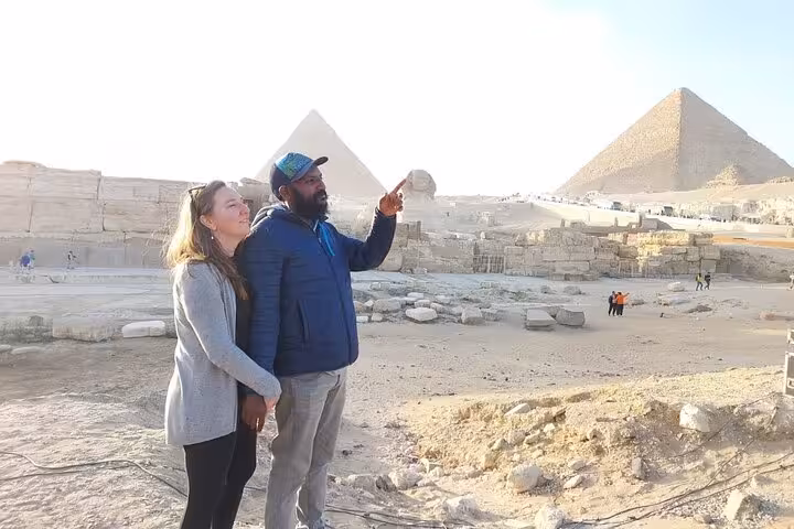 Private Cairo Airport tour guide with travelers at Giza Pyramids, scenic stop before Egyptian Museum and Coptic Cairo