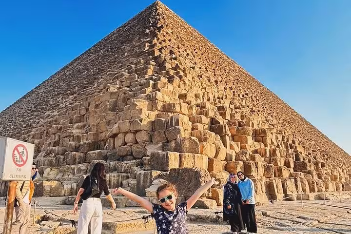 Traveler celebrating at the Great Pyramid of Giza on private Cairo Airport transfer tour to pyramids and museum