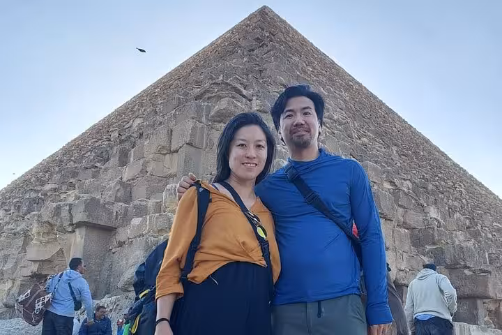 Travelers pose by the Great Pyramid of Giza on a private Cairo Airport transfer tour to pyramids and museum