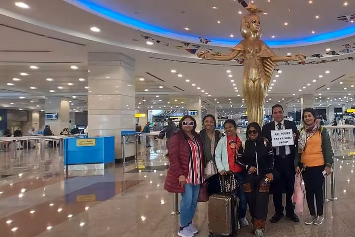 Travelers gather under a golden statue at a bustling Cairo airport, ready to start their Private 3 Days tour.