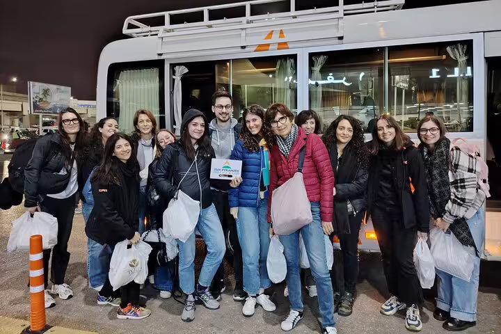 Group of tourists at night beside Cairo Airport shuttle bus, reliable Cairo airport transfer and meet-and-greet