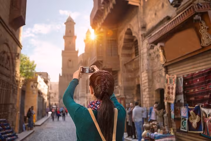 Traveler photographing historic Islamic Cairo bazaar street on full-day Cairo tour from Sharm by bus
