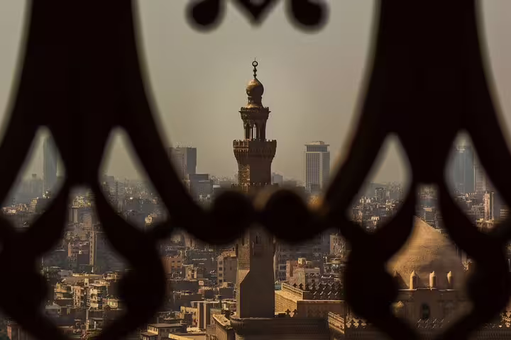 Cairo skyline view framed by Islamic lattice, highlighting a historic minaret on the Citadel and museum tour