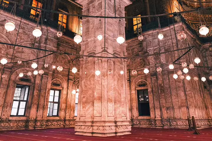 Inside Cairo Citadel mosque with hanging lamps and carved stone columns on a guided Cairo day tour