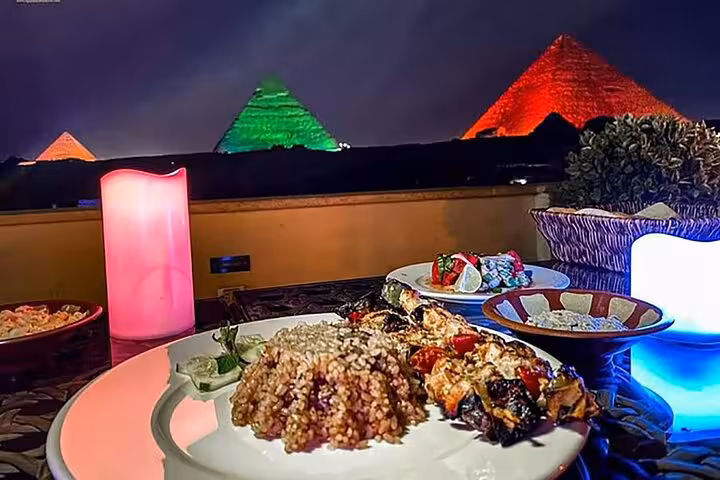 Dinner plate on terrace with Giza Pyramids view during Cairo sound and light show at night