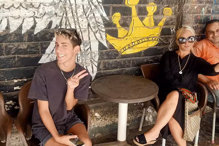 Guests relax at a Cairo café stop on a private food tour, posing by colorful street art mural