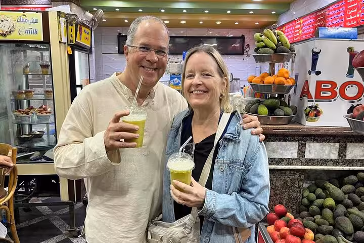 Couple sipping fresh sugarcane juice at a Cairo market stall during a private Cairo food tour and walking tour