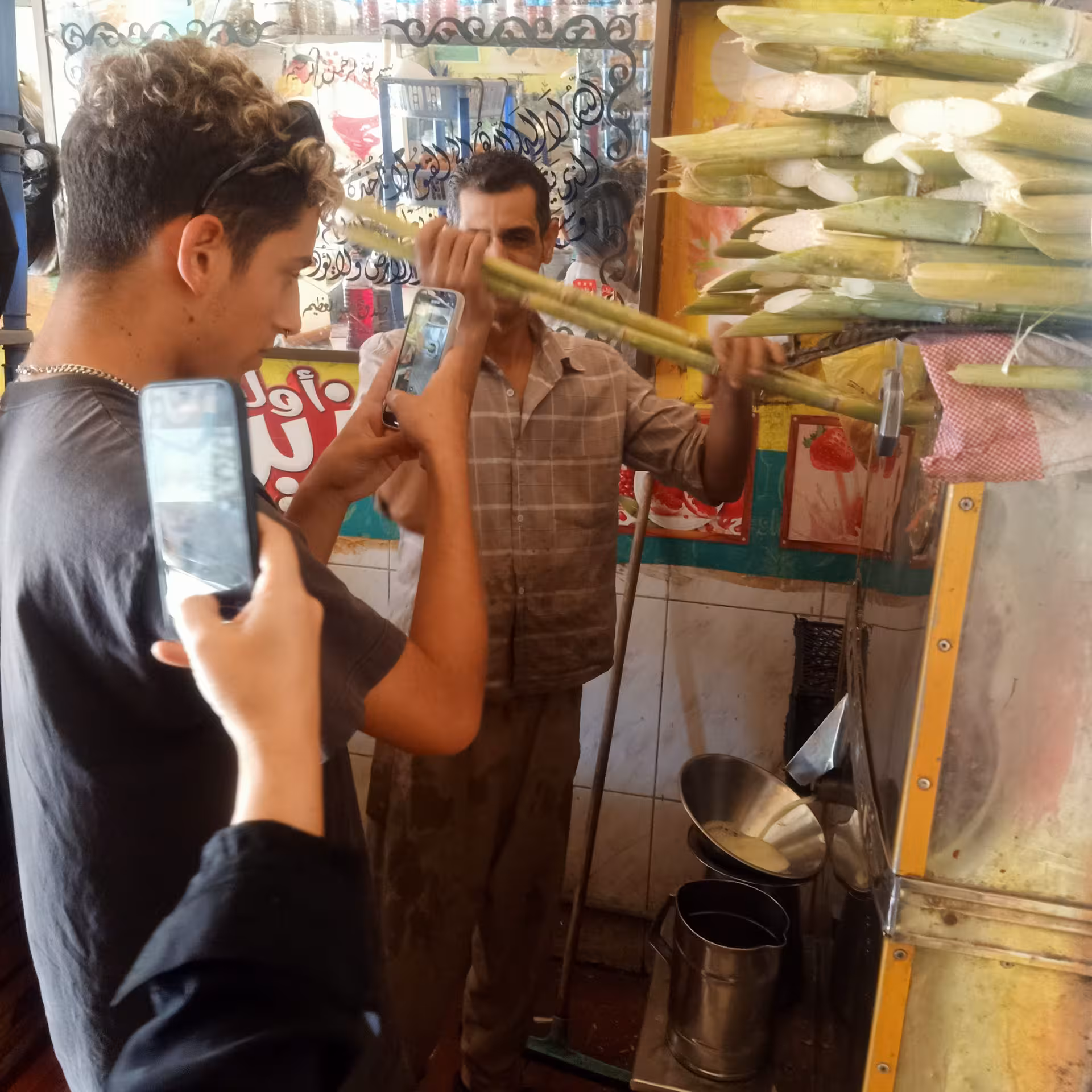 Tourists film a sugarcane juice vendor during a private Cairo food tour, tasting street drinks on a walking tour