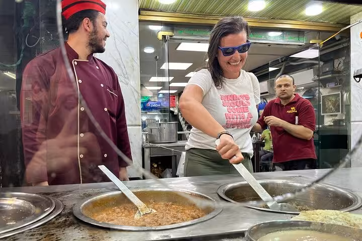 Tourist joyfully exploring Cairo's culinary scene, stirring traditional Egyptian dishes under chef's guidance.