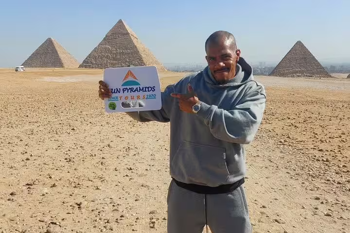 Tour guide holding sign with Giza pyramids backdrop on Cairo full day tour from Alexandria by car and driver