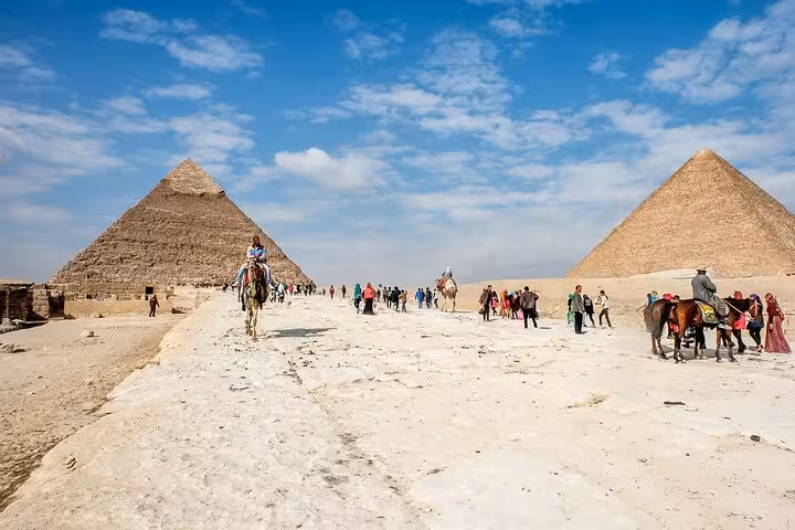 Tourists and camel riders between Giza Pyramids on a Cairo day trip from Sharm El Sheikh by bus
