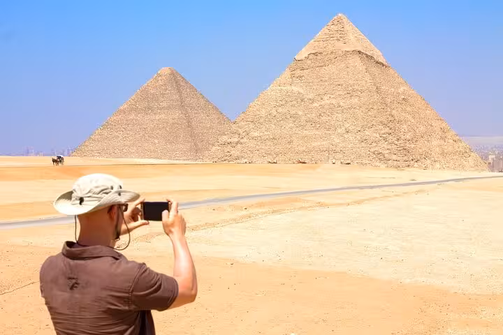 Tourist photographing the Great Pyramids of Giza on a full-day Cairo trip from Sharm El Sheikh by bus
