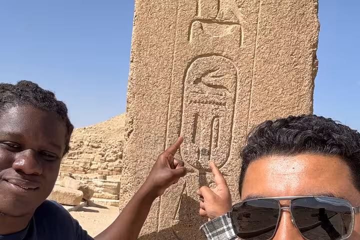 Guide explains ancient hieroglyphs on a stone pillar during private Cairo tour to Giza, Saqqara and Memphis