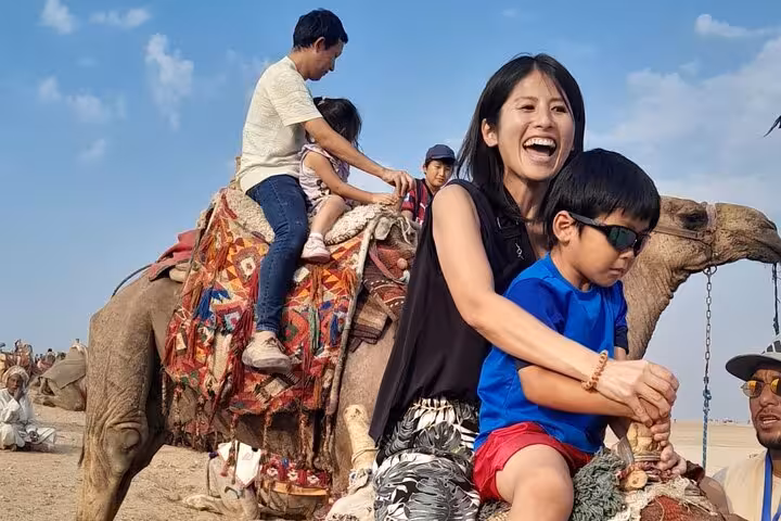 Family camel ride near Giza Pyramids during Cairo Airport layover tour, desert views and local experience