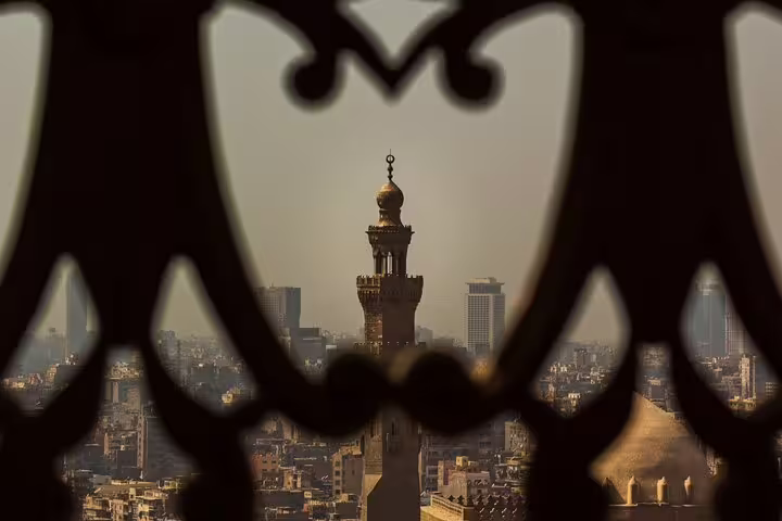 Minaret view over Cairo skyline framed by ornate lattice, highlight of Historical Cairo Mosques tour