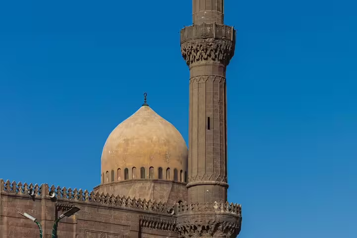 Historic Cairo mosque dome and minaret under blue sky, seen on Cairo by night tour near El Azhar Park