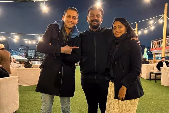 Three people enjoy an evening at a rooftop restaurant, highlighting the lively Cairo nightlife on the Private 3 Days Pyramids Tour.