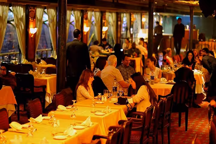 Guests dining aboard a Cairo Nile dinner cruise, enjoying buffet meal and live belly dance entertainment