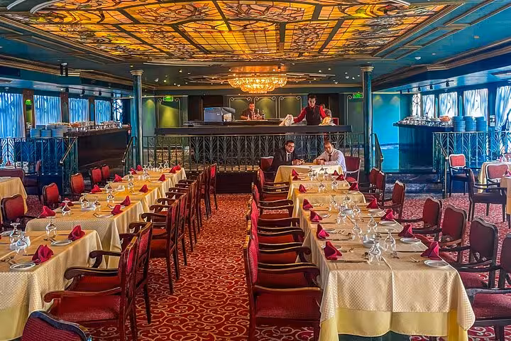 Cairo Nile dinner cruise restaurant with chandelier, set tables, and live show stage for belly dance