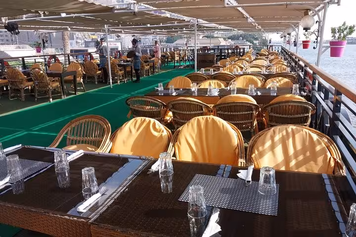 Open-air upper deck seating on Cairo Nile dinner cruise, set tables for evening belly dancing and folklore