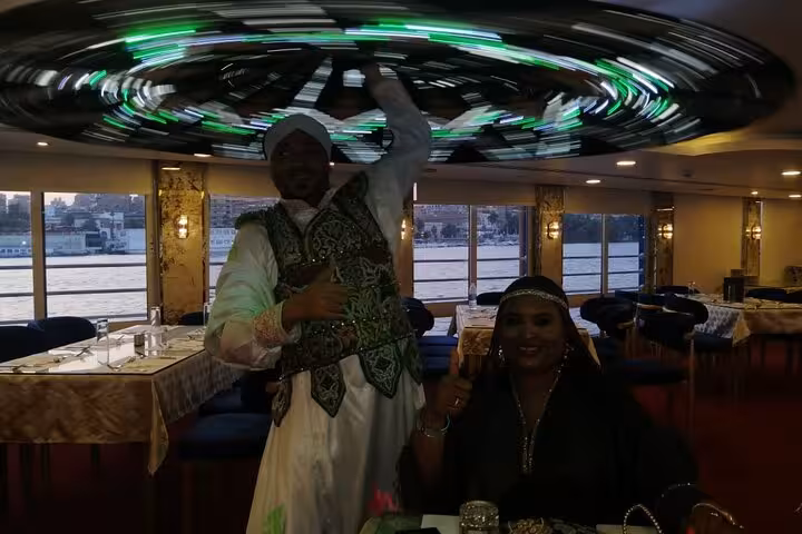 Tanoura dancer performing on Cairo Nile dinner cruise with guests seated, evening folklore show by the river