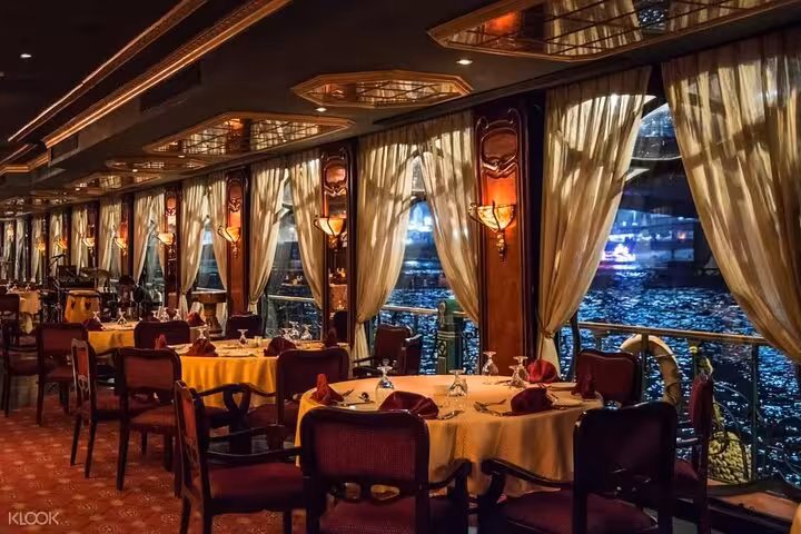 Elegant Nile dinner cruise dining room in Cairo with river views, set tables, and evening Tanoura show vibes