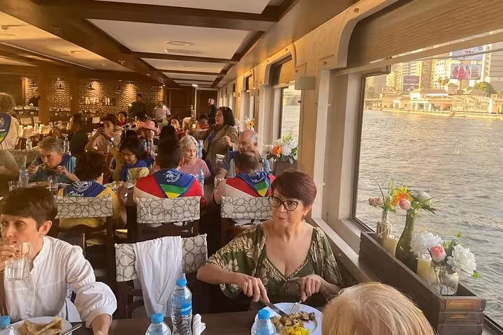 Window-side dining on Cairo Nile dinner cruise with river views, dinner service before belly dancing show