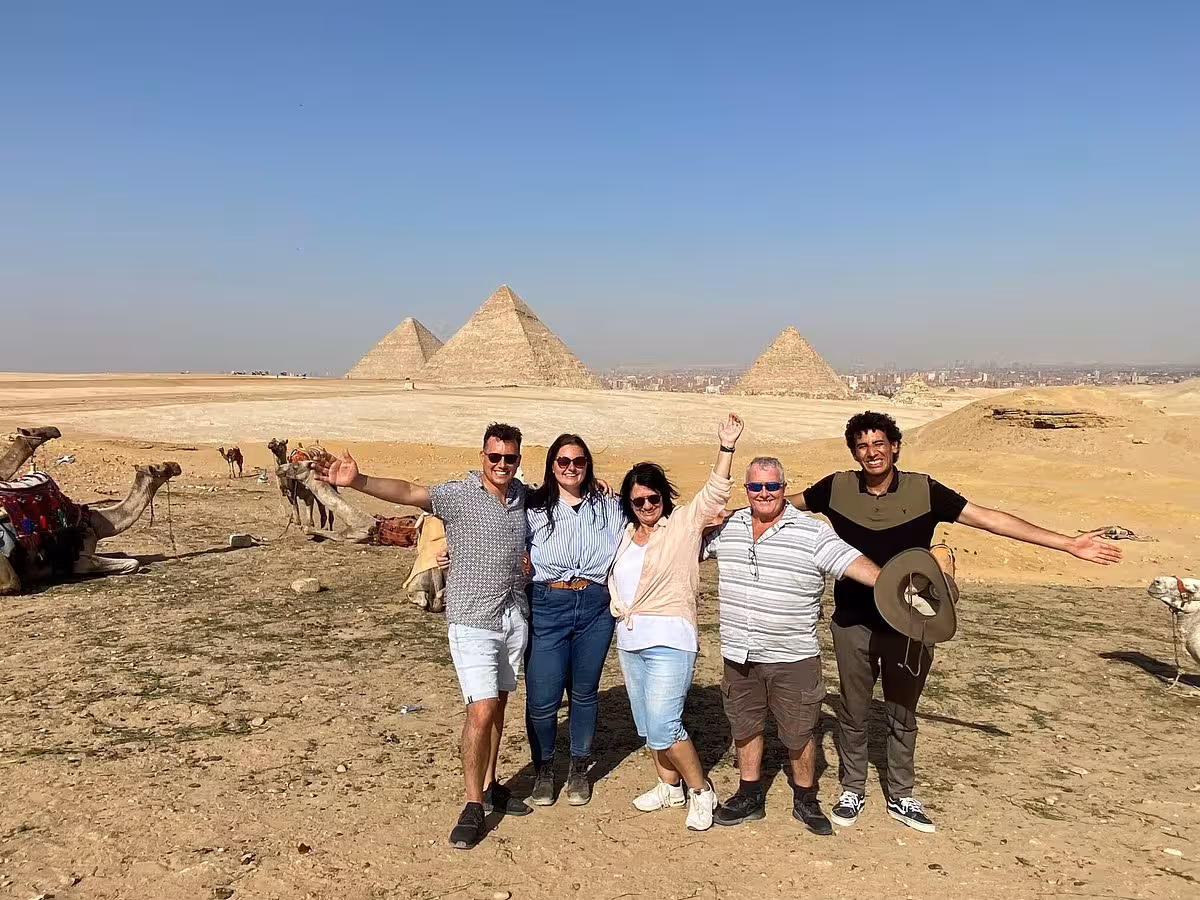 Happy group photo with camels and Pyramids of Giza on Cairo private tour including Memphis, Saqqara and lunch