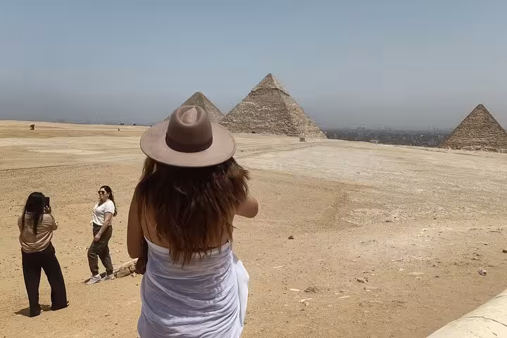 Traveler in sun hat overlooking the Pyramids of Giza plateau on a Cairo private tour with Egyptian lunch