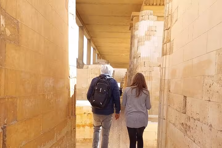 Tourists walking inside ancient stone corridor at Giza, part of 3-day Cairo pyramids and museum tour
