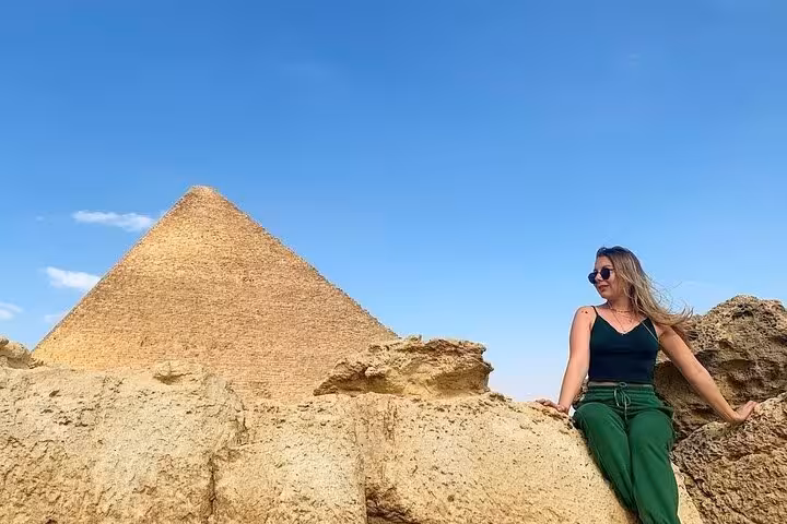 Traveler relaxing by a Giza pyramid under blue sky, highlight of semi-private Cairo pyramids tour from Hurghada