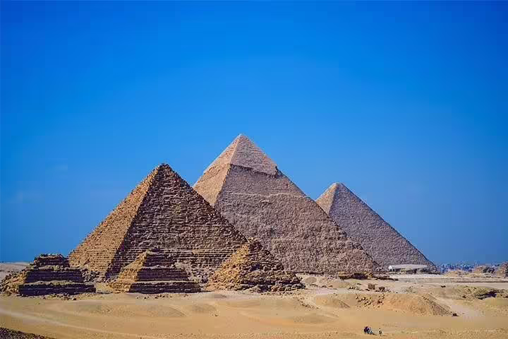Wide view of the Pyramids of Giza under clear blue sky, ideal backdrop for Cairo photo session add-on tour